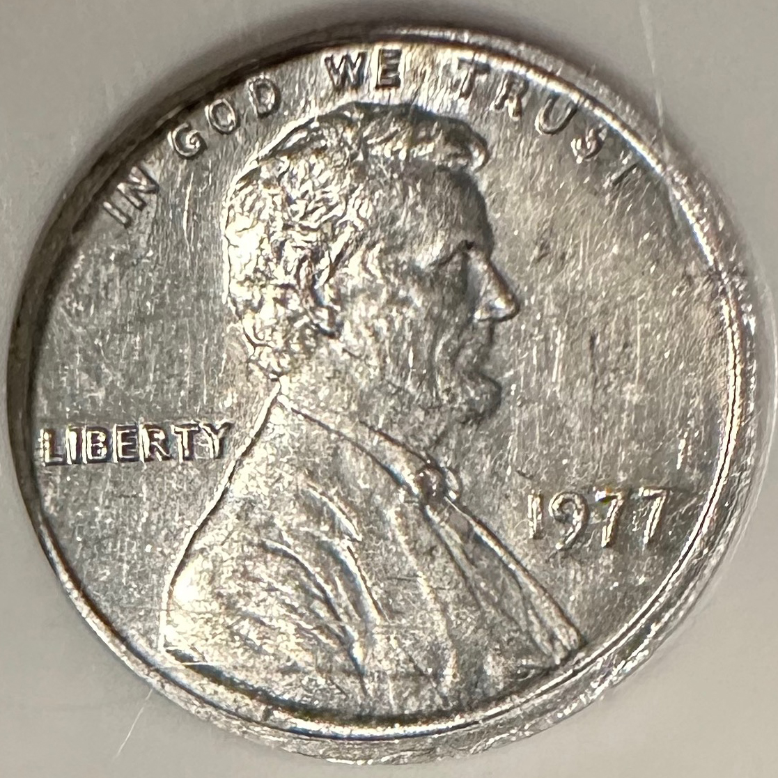 1977 Lincoln cent struck on Roosevelt dime planchet compared to normal copper 1977 penny showing size and color difference